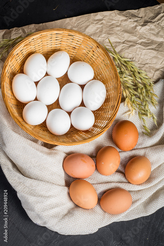 Chicken eggs in the basket on black wooden background. Copy space