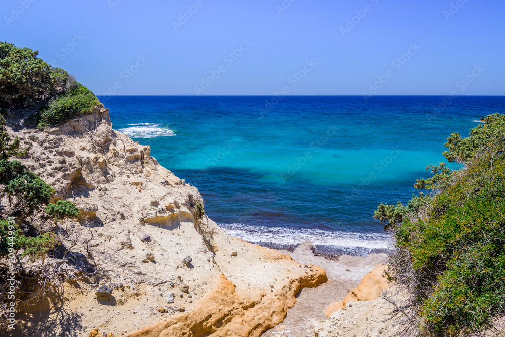 Beach, Greece - Kos Island, Kefalos: Picturesque deep blue Caribbean Bay with wild sea of ​​Greek Agais and steep sandstone cliffs, perfect for wind surfers with heavy waves