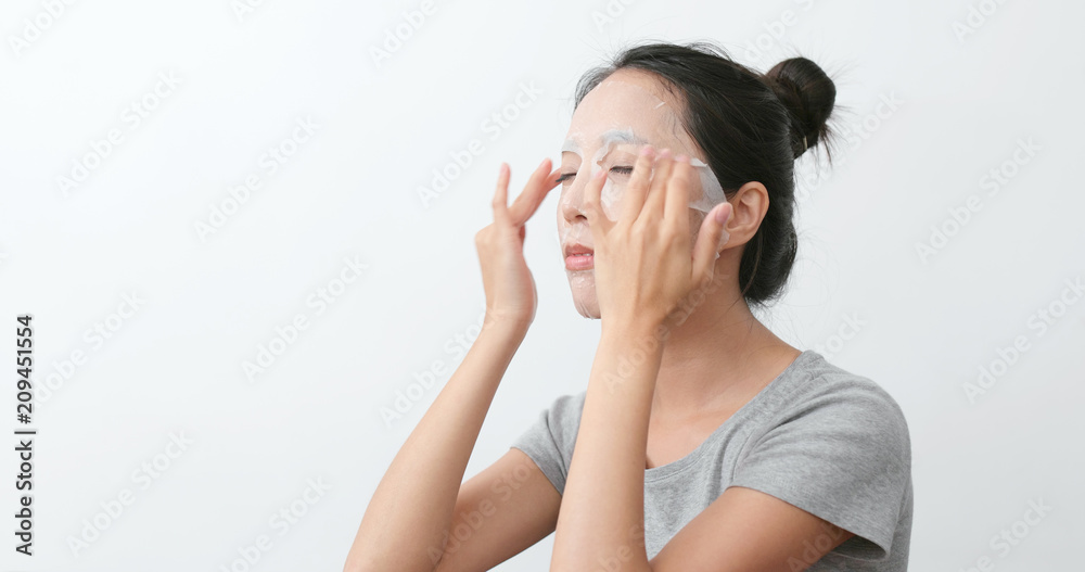 Woman apply paper mask and massaging on face Woman apply paper mask and massaging on face