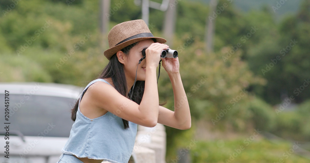 Woman travel with her car and looking though the binocular and enjoy natural landscape