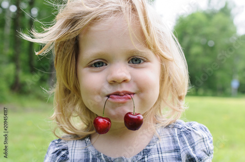 little girl with a sweet cherry in her mouth