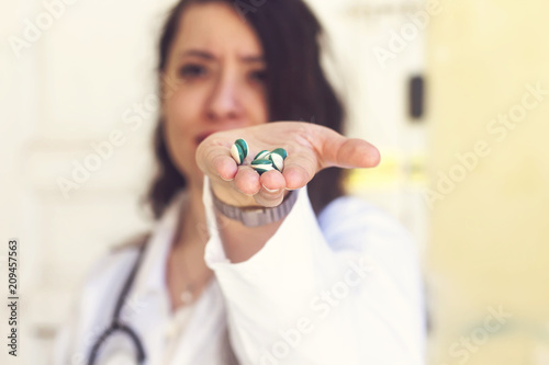 beautiful arabic doctor woman holding a green pills 