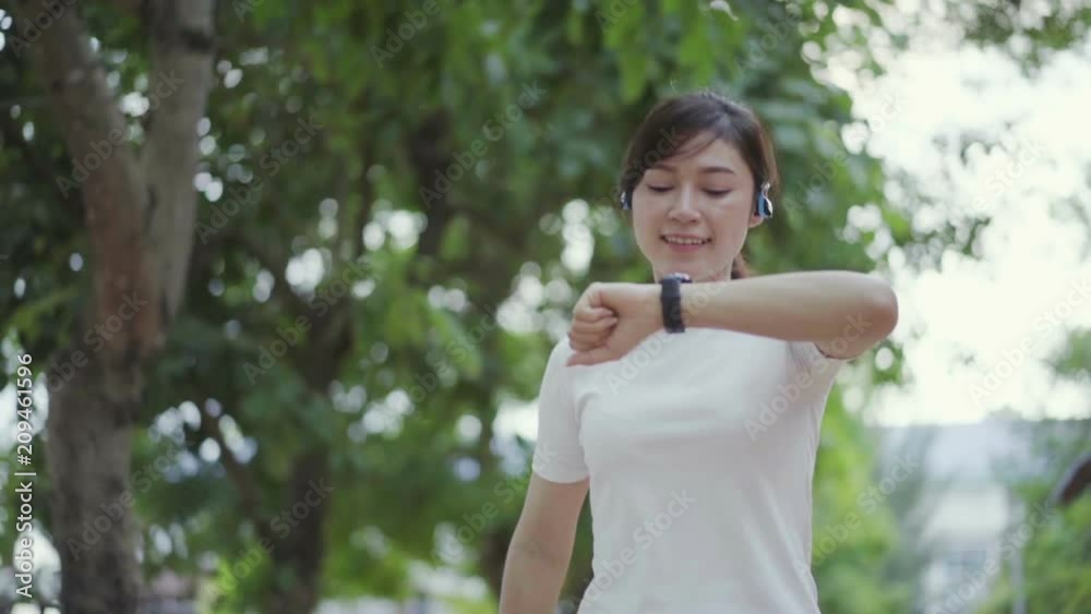 slow-motion of woman is running with wireless earphones and checking her smart watch slow-motion of woman is running with wireless earphones and checking her smart watch