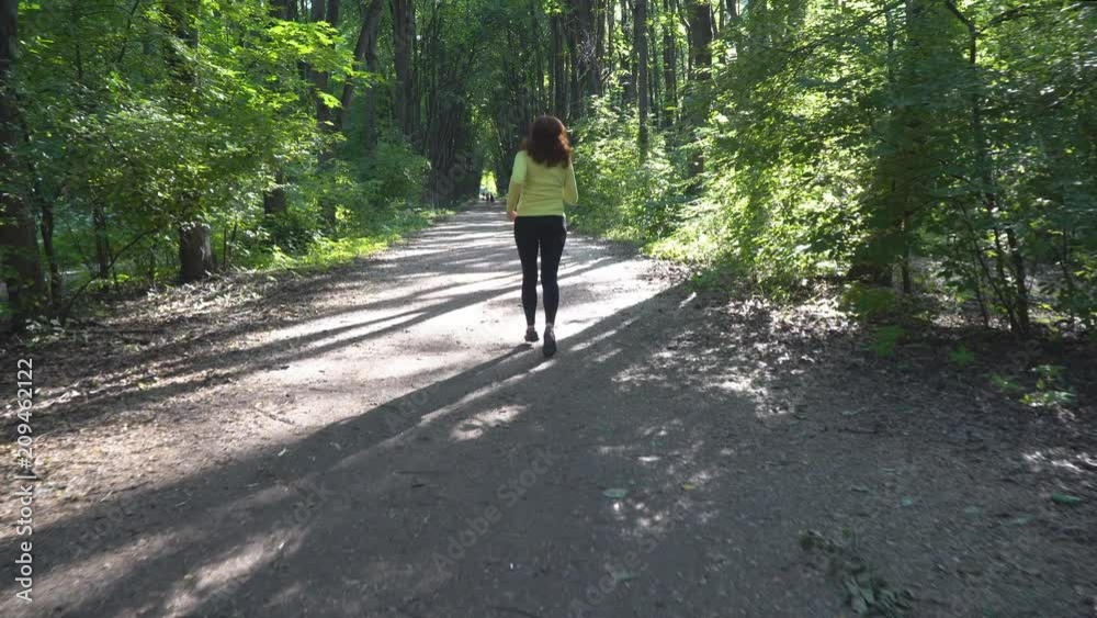Slender and athletic middle-aged woman is engaged in running outdoors in a summer Park Slender and athletic middle-aged woman is engaged in running outdoors in a summer Park