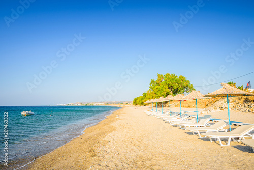 Beaches, Greece, Kos Island, Kardamena: beautiful holiday setting on a secluded beach with umbrellas on the Greek Aegean Sea with turquoise waters and a picturesque bay and islands in the background