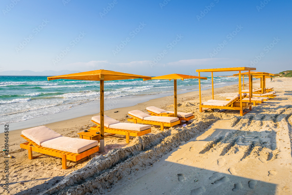 Beaches, Greece, Kos Island, Kochylari: beautiful holiday setting on a secluded beach with umbrellas on the Greek Aegean Sea with turquoise waters and a picturesque bay and islands in the background