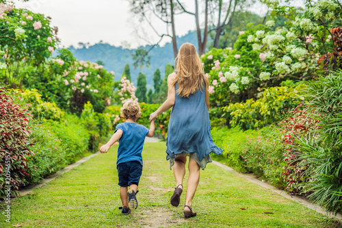 Mom and son are running around in the blooming garden. Happy family life style concept photo