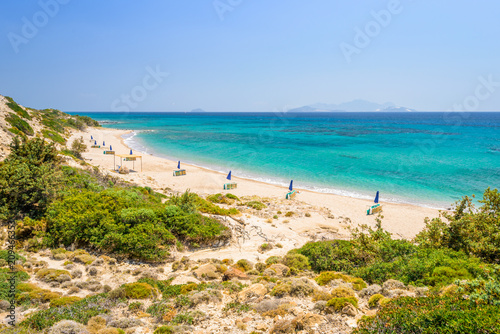 Beaches, Greece, Kos Island, Cap Helona: beautiful holiday setting on a secluded beach with umbrellas on the Greek Aegean Sea with turquoise waters and a picturesque bay and islands in the background