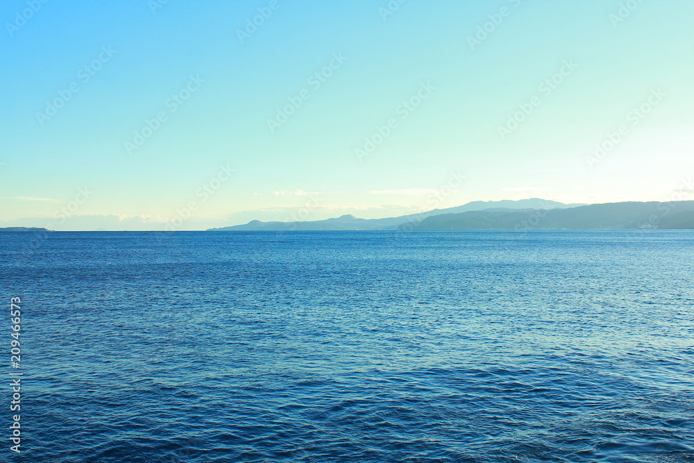 light blue sea and sky with land and mountains in distance