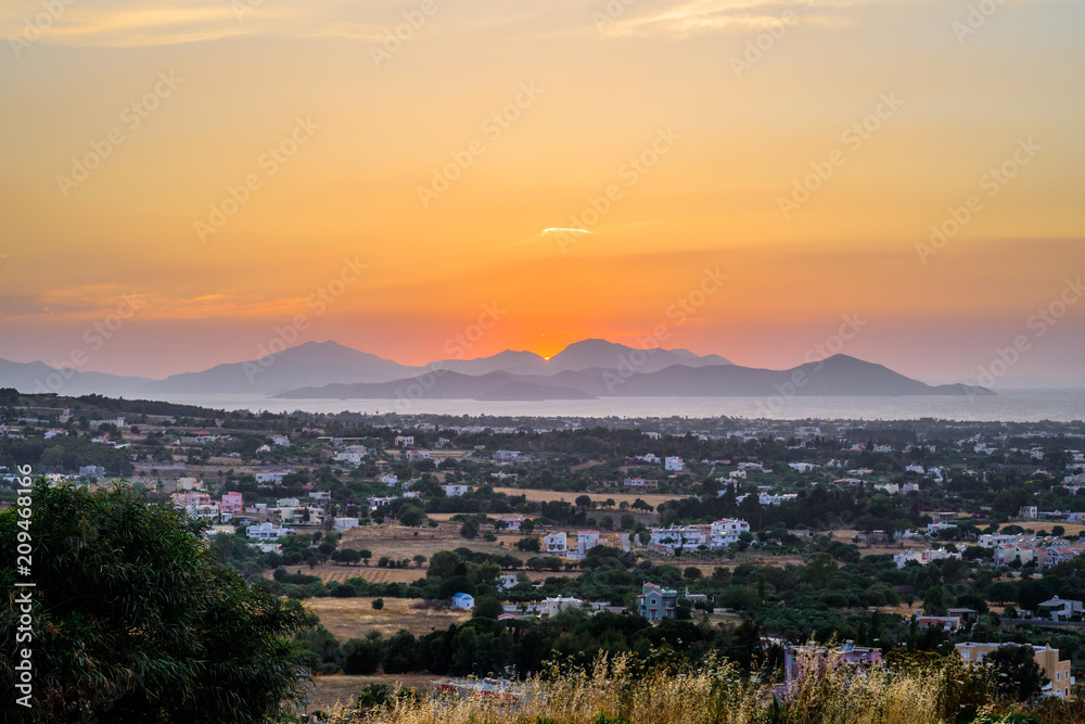 Kos Island, Town, Kalymnos, Greece - Warm sunset over the greek mediterranean sea near the turkish coast, viewed from the mountains of the island in a picturesque garden with many wildflowers
