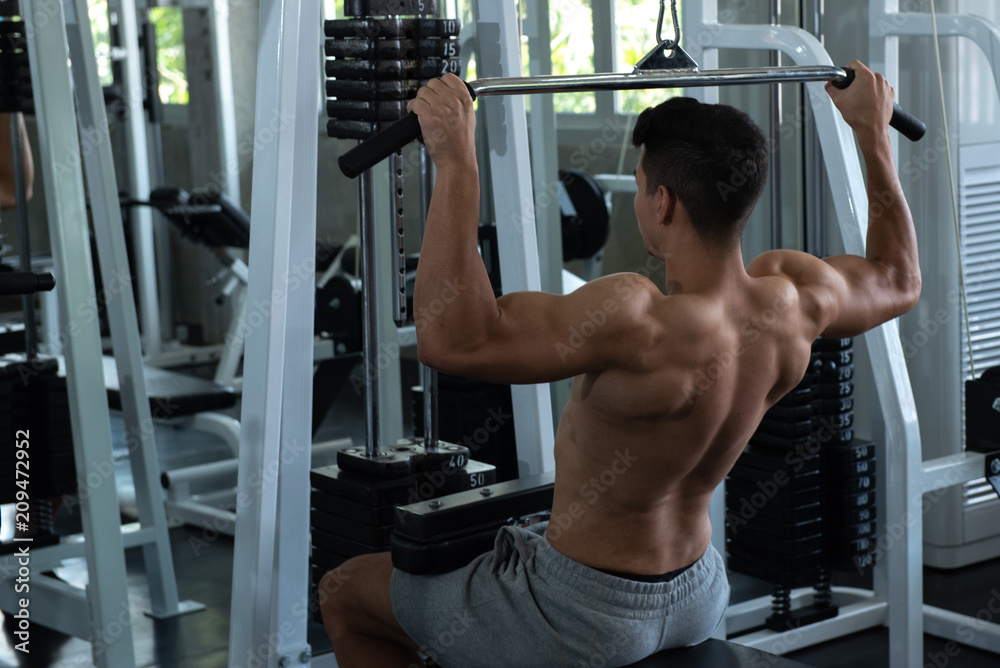 Portrait of young man using weight lifting equipment to build a massive chest and arm at indoor sport gym , bodybuilder concept. Portrait of young man using weight lifting equipment to build a massive chest and arm at indoor sport gym , bodybuilder concept.