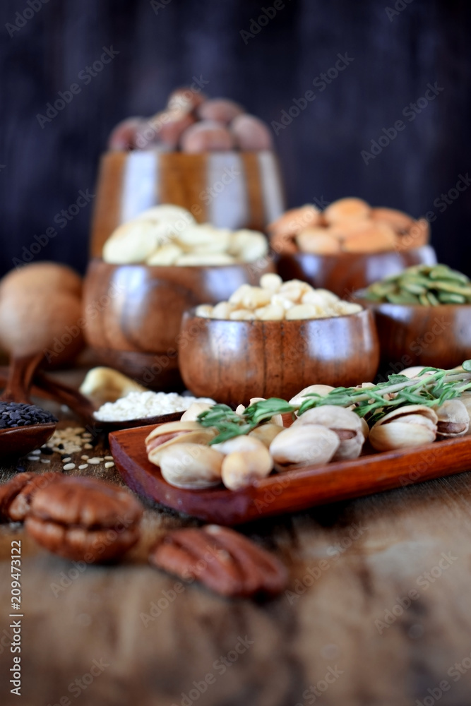 Different nuts and seeds in wooden spoons and bowls on a table Different nuts and seeds in wooden spoons and bowls on a table