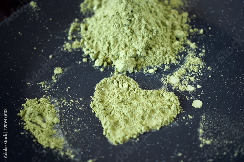 Green matcha tea powder forming a heart on a dark plate