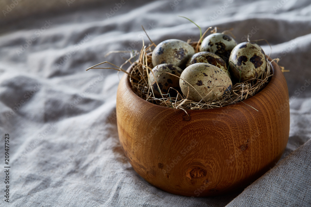 Fresh quail eggs in a wooden bowl on a dark wooden background, top view, close-up Fresh quail eggs in a wooden bowl on a dark wooden background, top view, close-up
