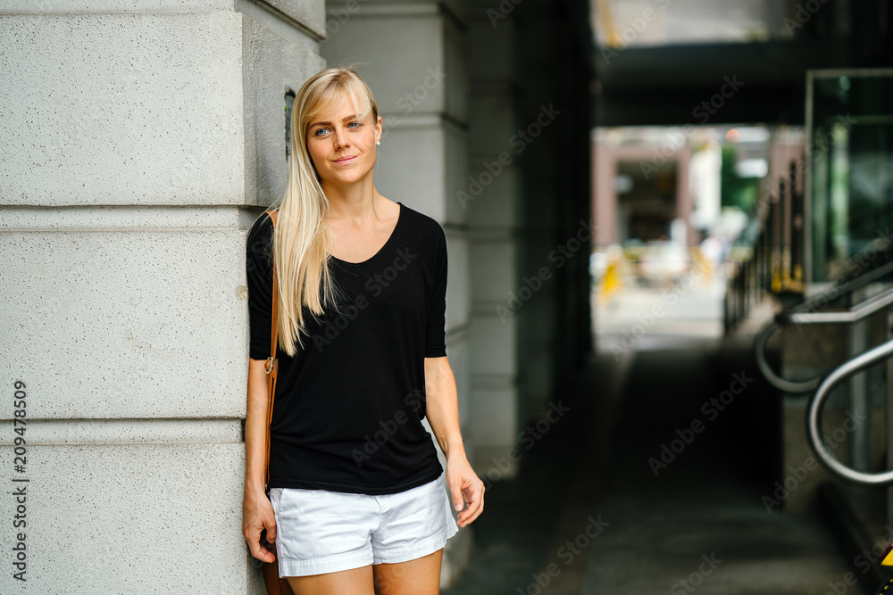 Portrait of a young and beautiful blonde woman with blue eyes. She is casually and comfortably dressed as she wanders around the new city.