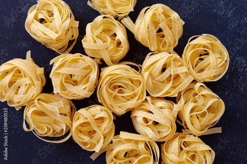 Close up of a raw dry italian pasta fettuccine on black chalkboard.