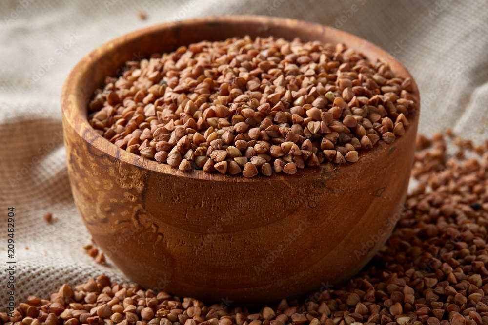 Bowl full of buckwheat grains on rustic wooden table, close-up, selective focus, shallow depth of field. Bowl full of buckwheat grains on rustic wooden table, close-up, selective focus, shallow depth of field.
