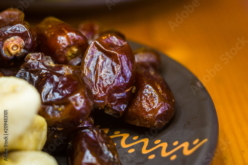 dried dates and figs in a ceramic plate on a wooden table
