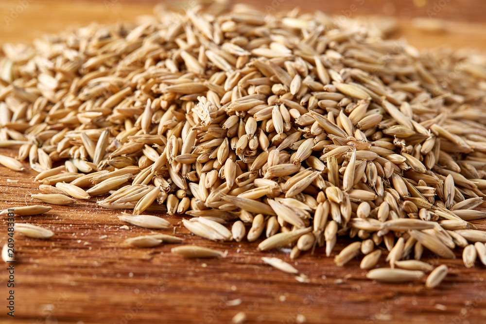 Obraz premium Pile of unpeeled oat grains on homespun tablecloth background, top view, close-up, macro, selective focus.