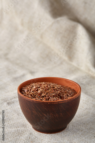 Bowl full of buckwheat grains on rustic wooden table, close-up, selective focus, shallow depth of field.