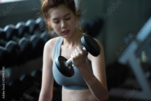 Attractive young sports woman lifting weights in the sport gym ,bodybuilding and loose weight concept.