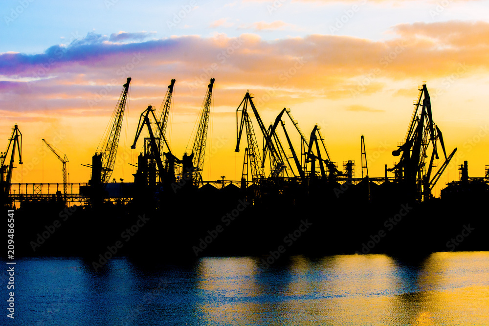 Silhouette of a crane. Cranes at the port. Silhouette of harbor at sunset. Sea port. Sunset at the port.