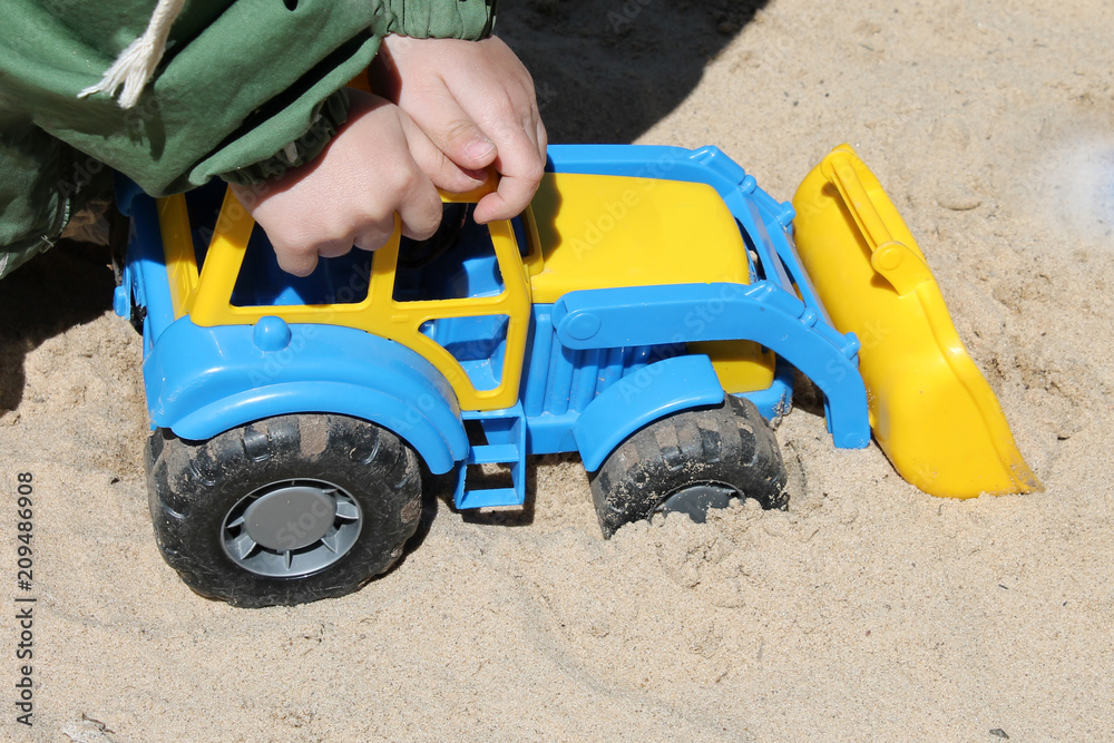 the child plays a toy car in the sandbox the child plays a toy car in the sandbox