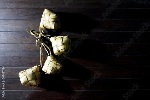Ketupat rice dumpling, a Malaysia traditional food for Hari Raya celebration in a rustic wooden texture white background. 