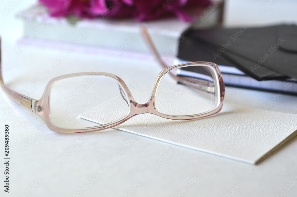 Bold violet pink peonies with blush pink glasses on a desk. Elegant feminine styled desktop workspace.Concept of working from home office and studying.
Bold violet pink peonies with blush pink glasses on a desk. Elegant feminine styled desktop workspace.Concept of working from home office and studying.