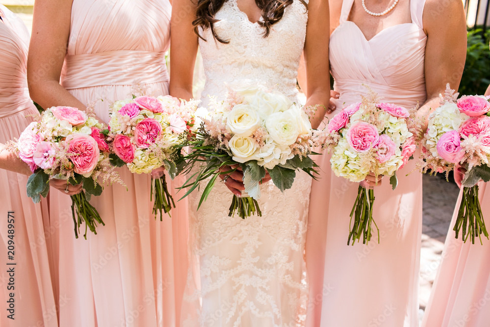 Close up of pink rose bouquets being held by bride standing with her bridesmaids - obrazy, fototapety, plakaty 