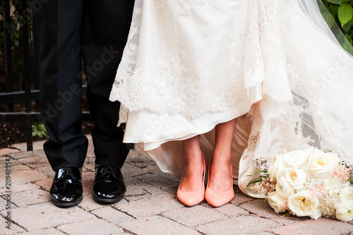 Close up of feet of bride and groom with flowers laying on ground 