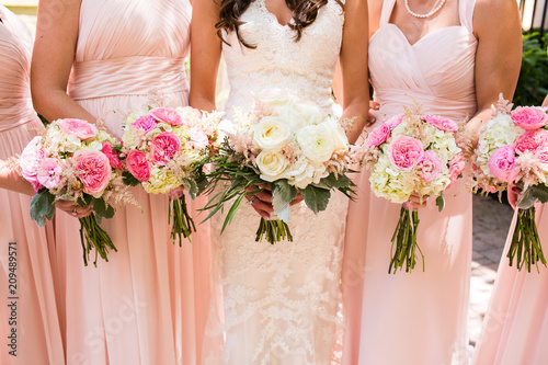 Close up of pink rose bouquets being held by bride standing with her bridesmaids photo
