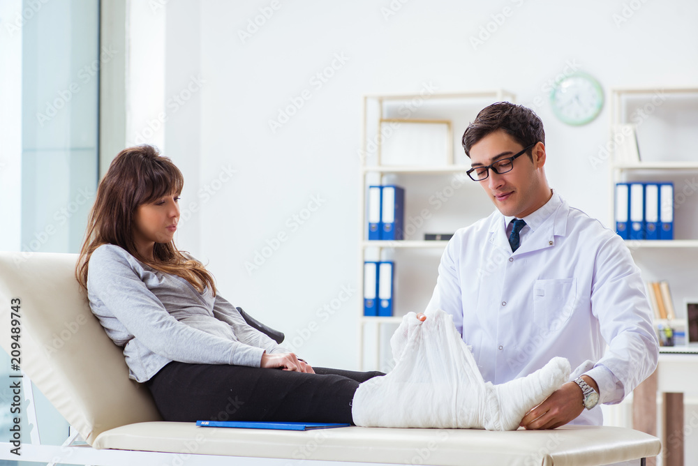Fototapeta premium Doctor examining patient with broken leg