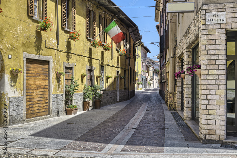 Obraz premium Lake Maggiore, Angera, Italy. Characteristic and picturesque alley (street - via Greppi) crosses the historic core of the village. Angera is known for the fortress of Angera (rocca di Angera)
