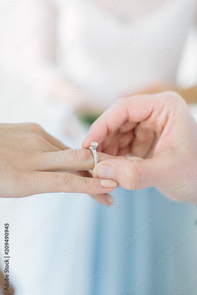 Beautiful smiling master of wedding ceremony holding glass box with wedding rings. The groom is wearing bride's ring on her finger. Beautiful smiling master of wedding ceremony holding glass box with wedding rings. The groom is wearing bride's ring on her finger.
