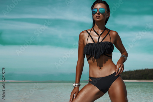 Beautiful bohemian styled woman, tanned girl at the beach, sexual black bikini, wet hair, holiday time, simmer fashion woman at tropical island,  stylish silver accessories, luxurious tanned body photo