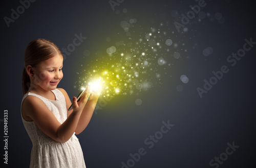 Little cute girl playing on sparkling tablet 