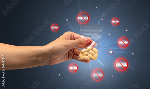 Hand giving pills with anti-drug concept and not allowed signs around