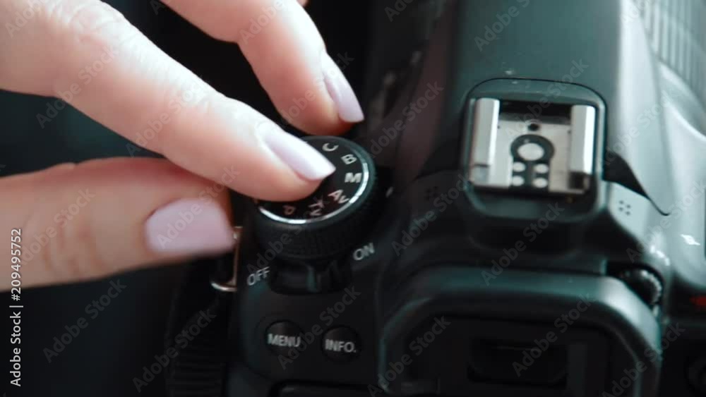 Hand holding and setting up a digital SLR camera. Close up of photographer hands on a photo camera on the set ot production shoot.