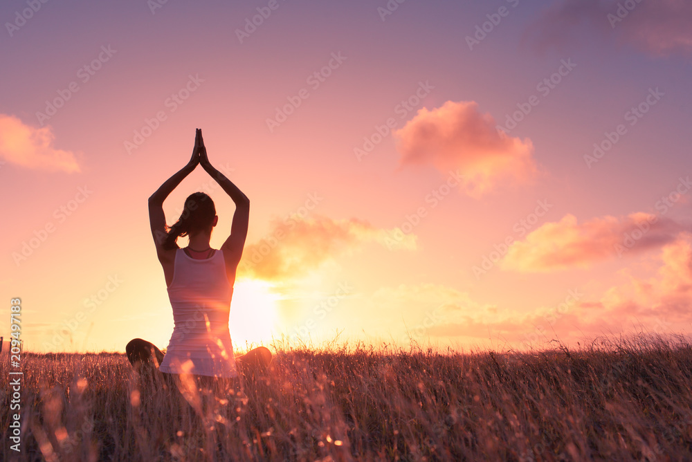 Peace and serenity. Female meditation outdoors in a open field at sunset.  - obrazy, fototapety, plakaty 