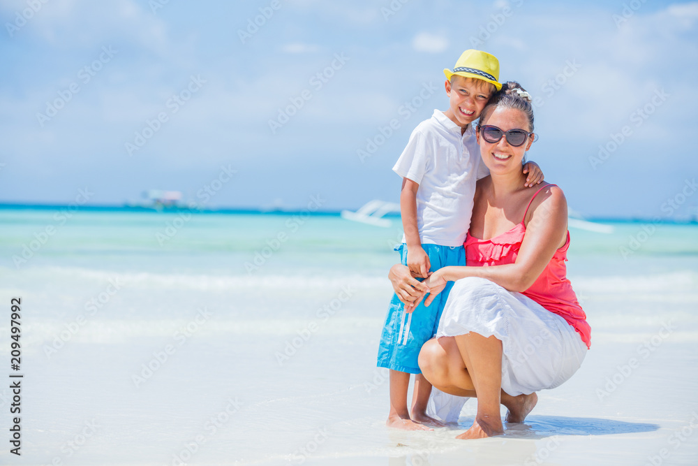 Happy family resting at beach in summer. Mother with boy resting on the beach. Young mother and her adorable little son on beach vacation Happy family resting at beach in summer. Mother with boy resting on the beach. Young mother and her adorable little son on beach vacation