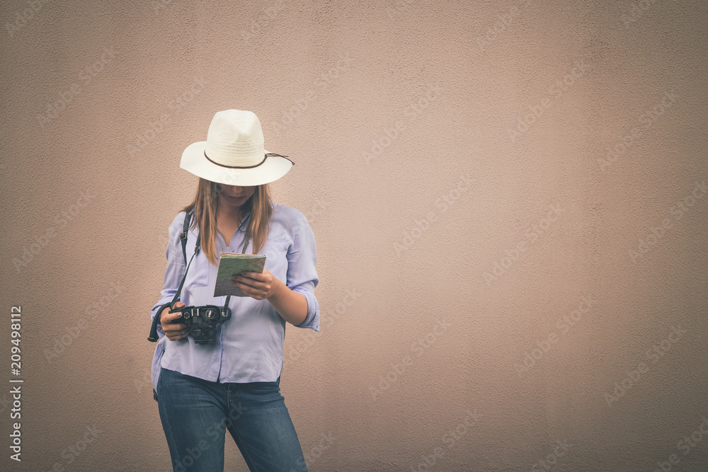 Young teenage tourist girl in straw hat, blue shirt and jeans stands with backpack and camera on wall background, portet.The concept of leisure and tourism in vintage style trend with copy space Young teenage tourist girl in straw hat, blue shirt and jeans stands with backpack and camera on wall background, portet.The concept of leisure and tourism in vintage style trend with copy space
