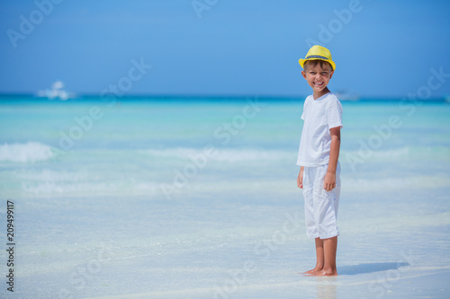 Happy child in yellow hat on beach. Summer vacation concept