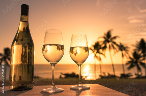 Romantic  and relaxing beach holiday for two background. Pair of wine glasses on the beach at sunset. 