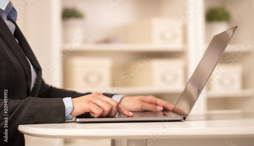 Business woman below chest working on laptop in a cozy homey environment with secured connection concept  