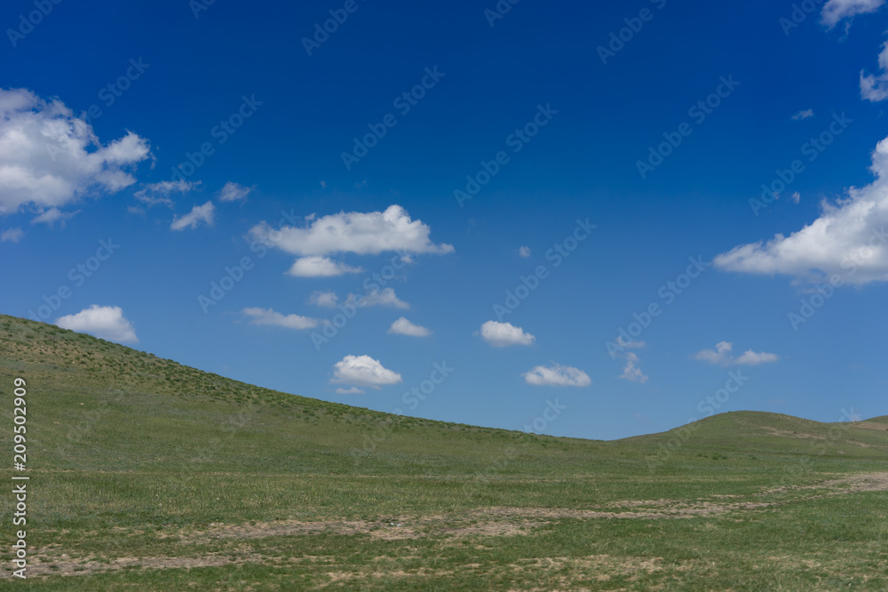 Natural landscape with hills on blue sky background.