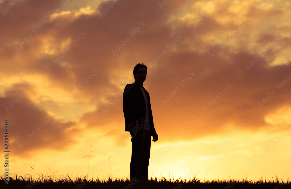 Silhouette of man standing against sunset. 