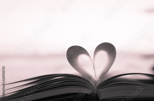 Close up heart shape from paper book on sand in the beach with vintage filter blur background photo