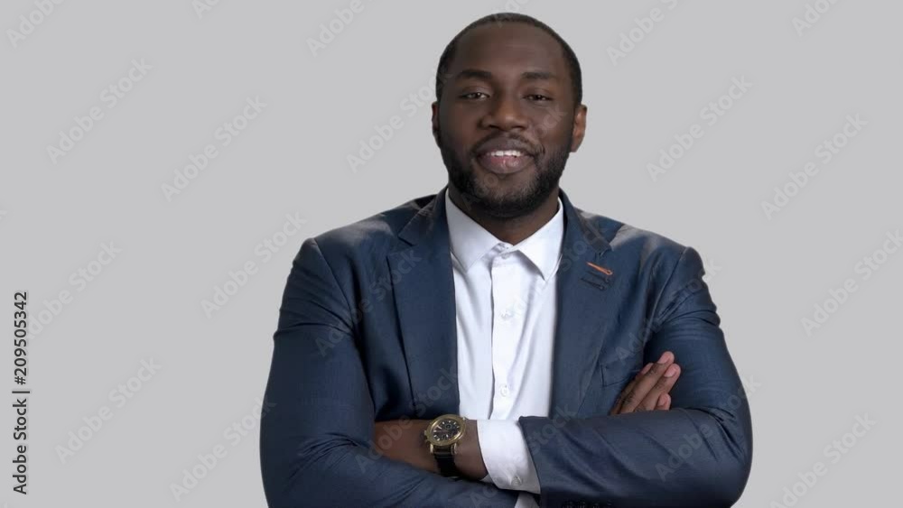 Smiling afro-american businessman with arms crossed. Cheerful african-american guy in business suit posing on grey background. Smiling afro-american businessman with arms crossed. Cheerful african-american guy in business suit posing on grey background.