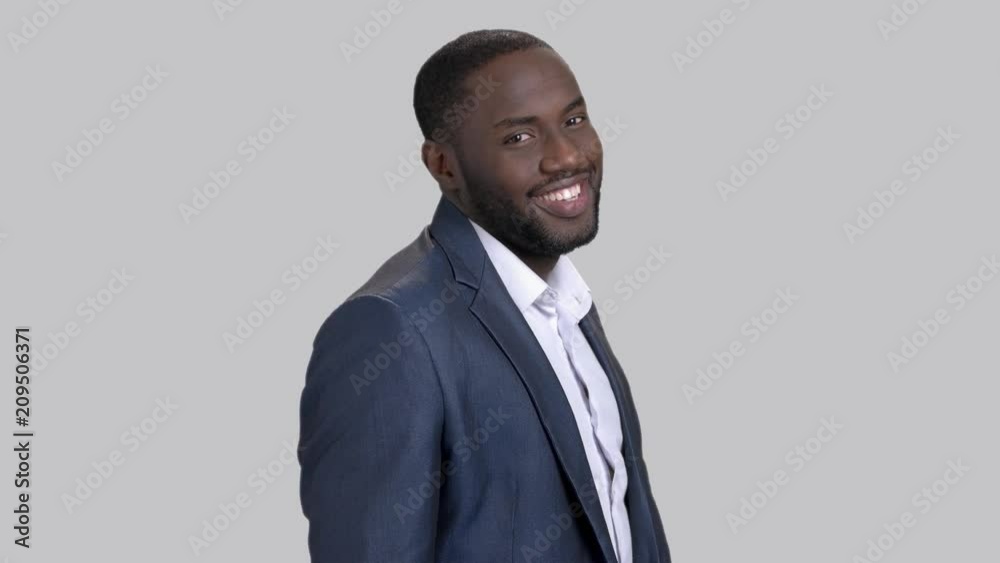 Joyful macho-man on grey background. Smiling afro-american businessman is adjusting his shirt. Successful black businessman. Joyful macho-man on grey background. Smiling afro-american businessman is adjusting his shirt. Successful black businessman.